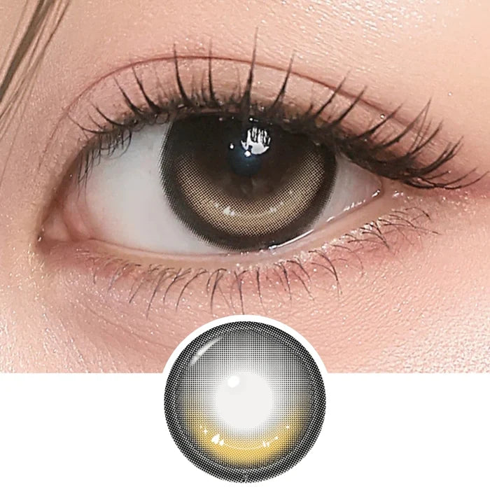 Close-up of eye with long lashes wearing i-Girl One Pick Dear One Honey contact lens from EyeCandys, showing warm honey-brown iris color and detailed lens design