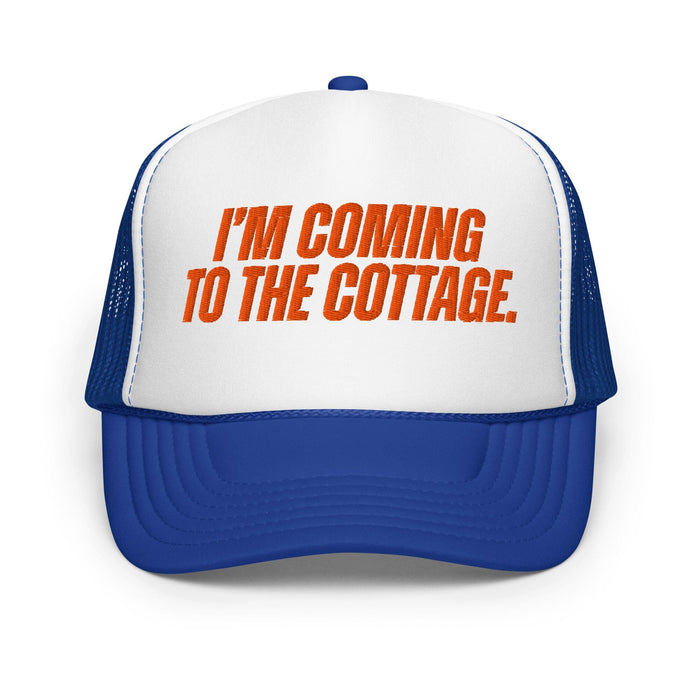 A blue and white trucker hat with orange text on the front panel reading 'I'M COMING TO THE COTTAGE.' against a plain white background.