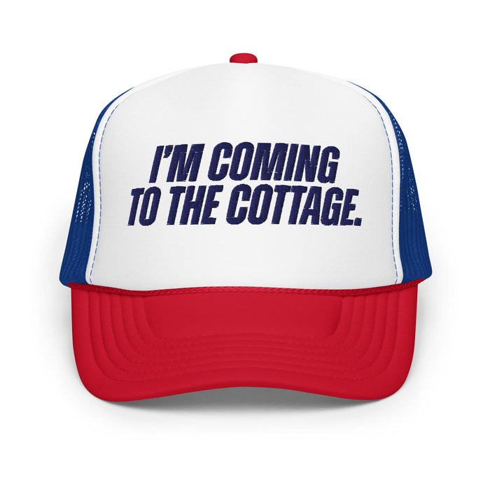 A red, white, and blue trucker hat with the text 'I'M COMING TO THE COTTAGE.' printed in navy blue on the white front panel, shown against a plain white background.