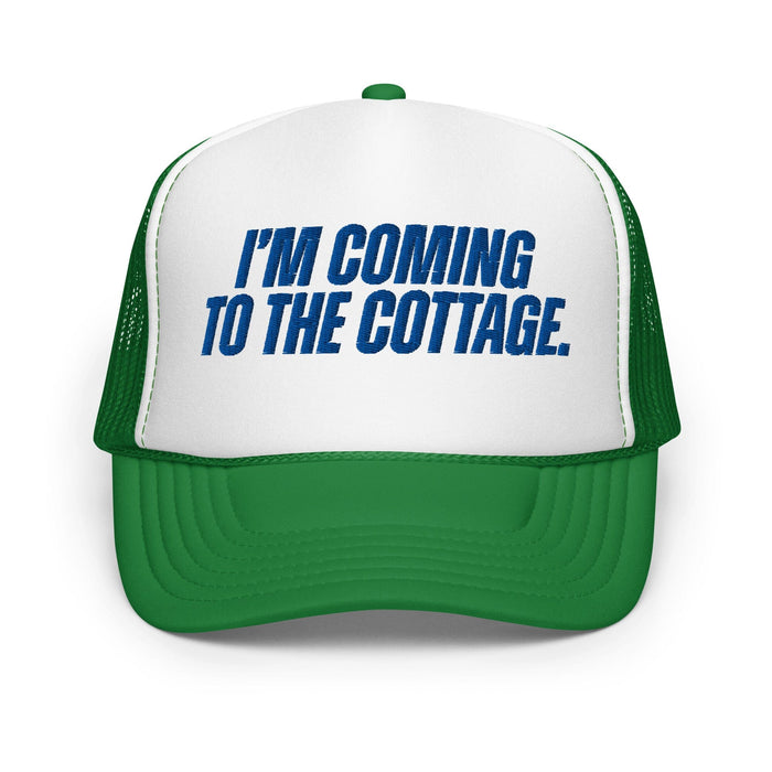 A green and white trucker hat with blue text on the front panel that reads 'I'M COMING TO THE COTTAGE.'